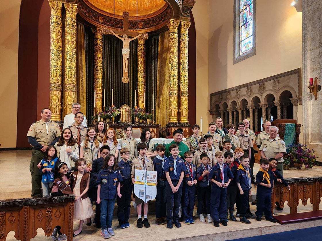 Uniformed scouts and adult leaders standing in a church