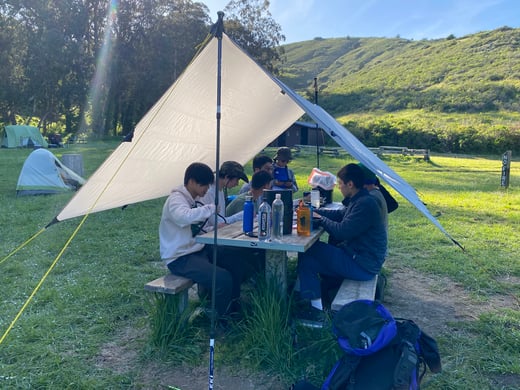 Troop 15 scouts sitting under a tent at picnic table
